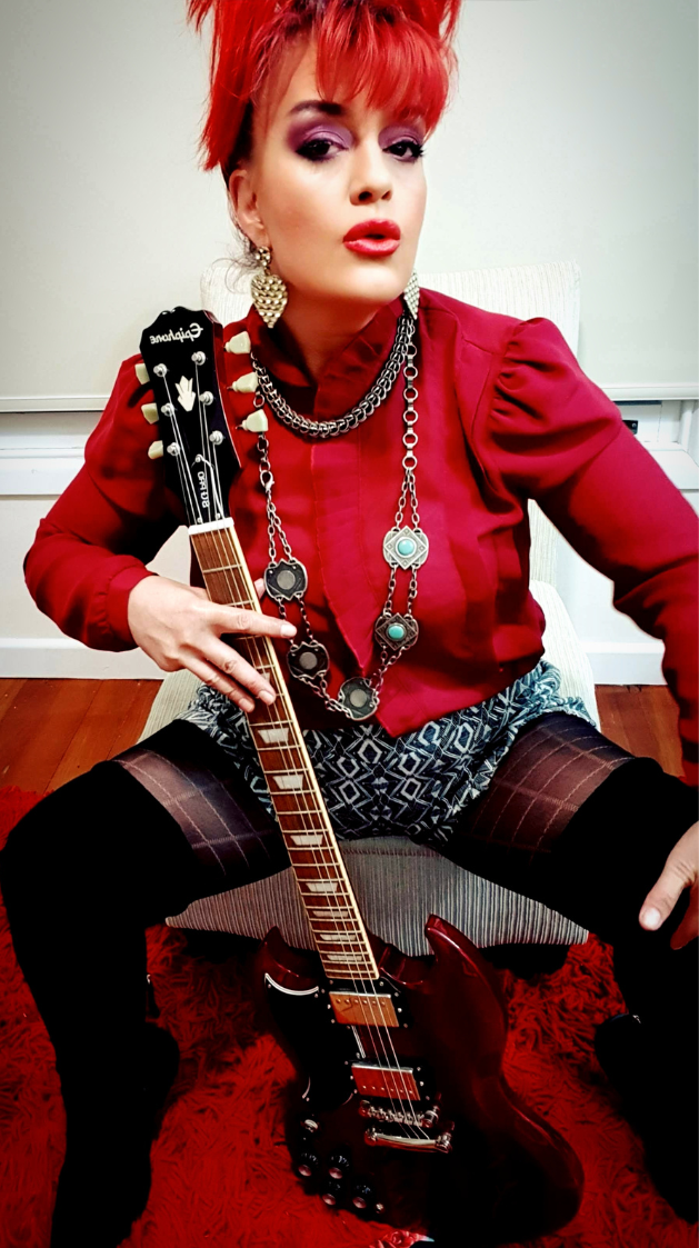 The Artist Red seated with her guitar